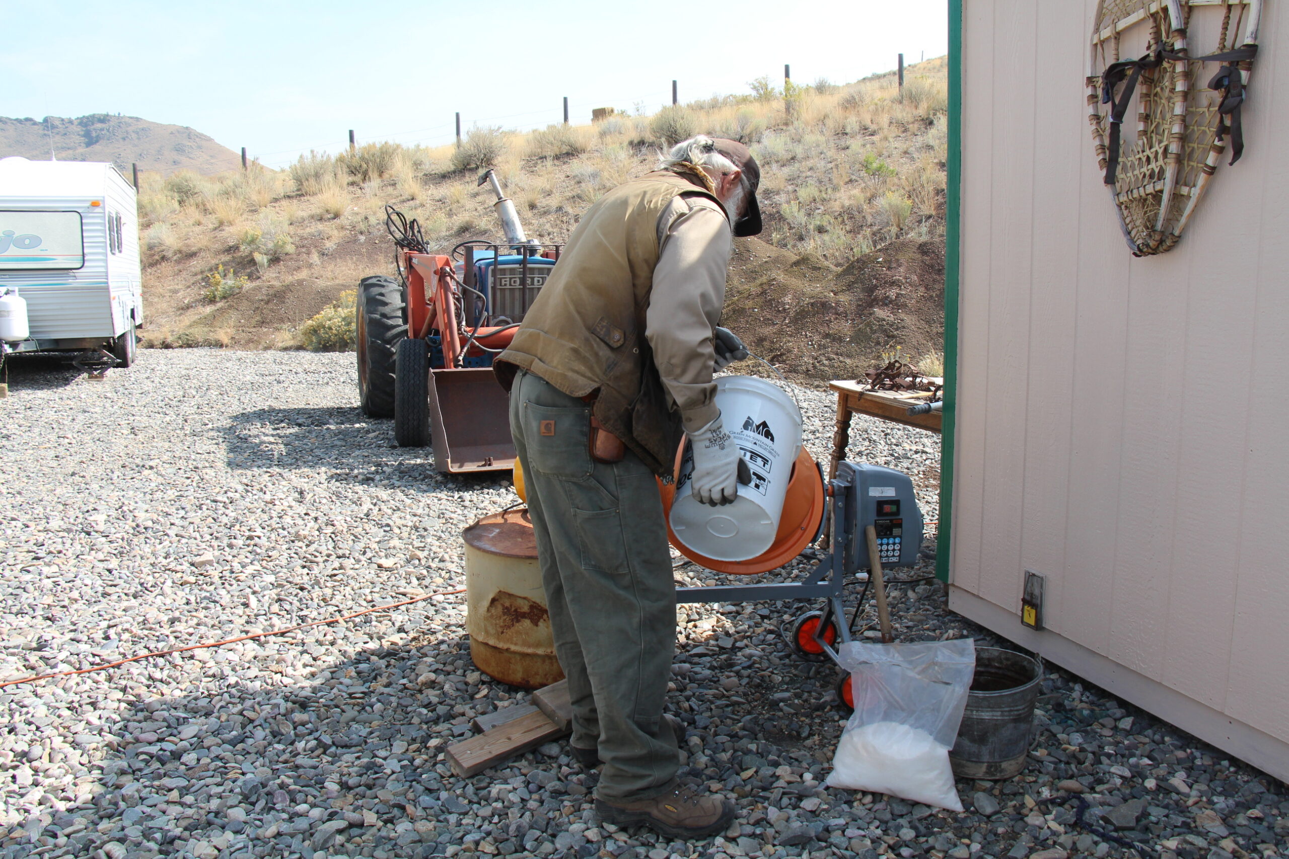 Pouring sifted dirt into cement mixer to make waxed dirt for trapping